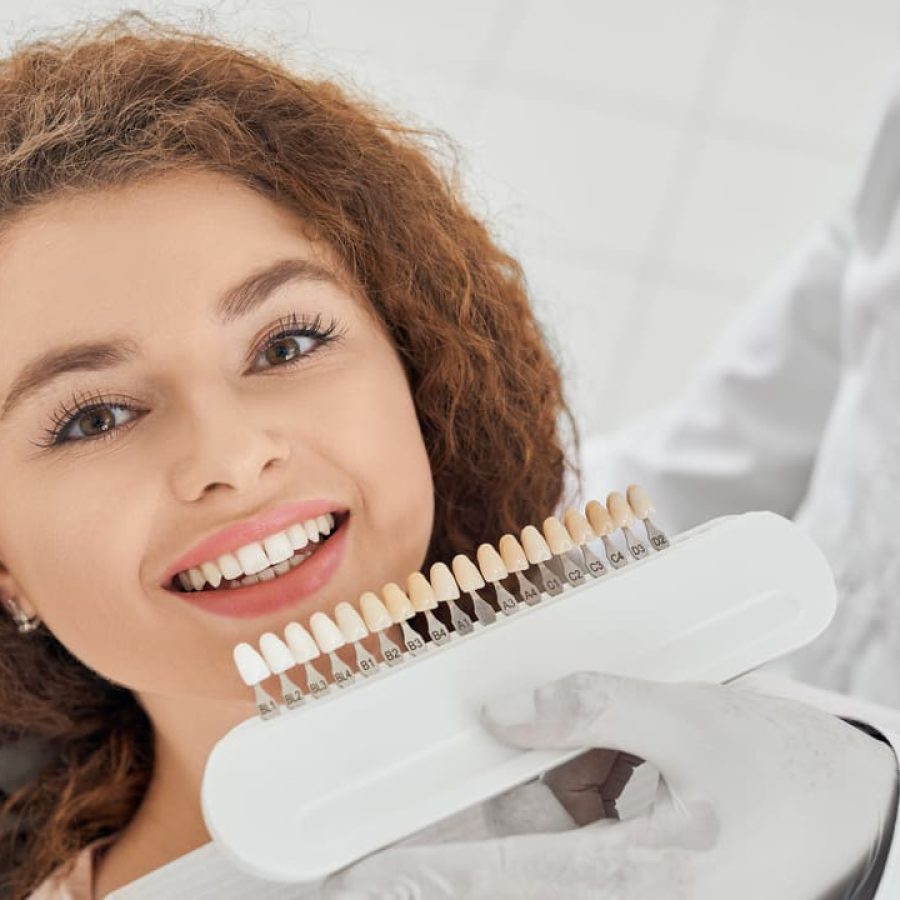 woman-smiling-while-male-dentist-keeping-teeth-color-range